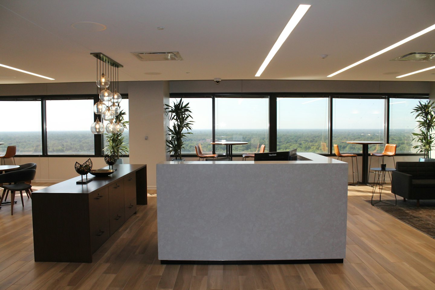 Moderna reception d'ufficio con scrivania grigia e credenza in legno.