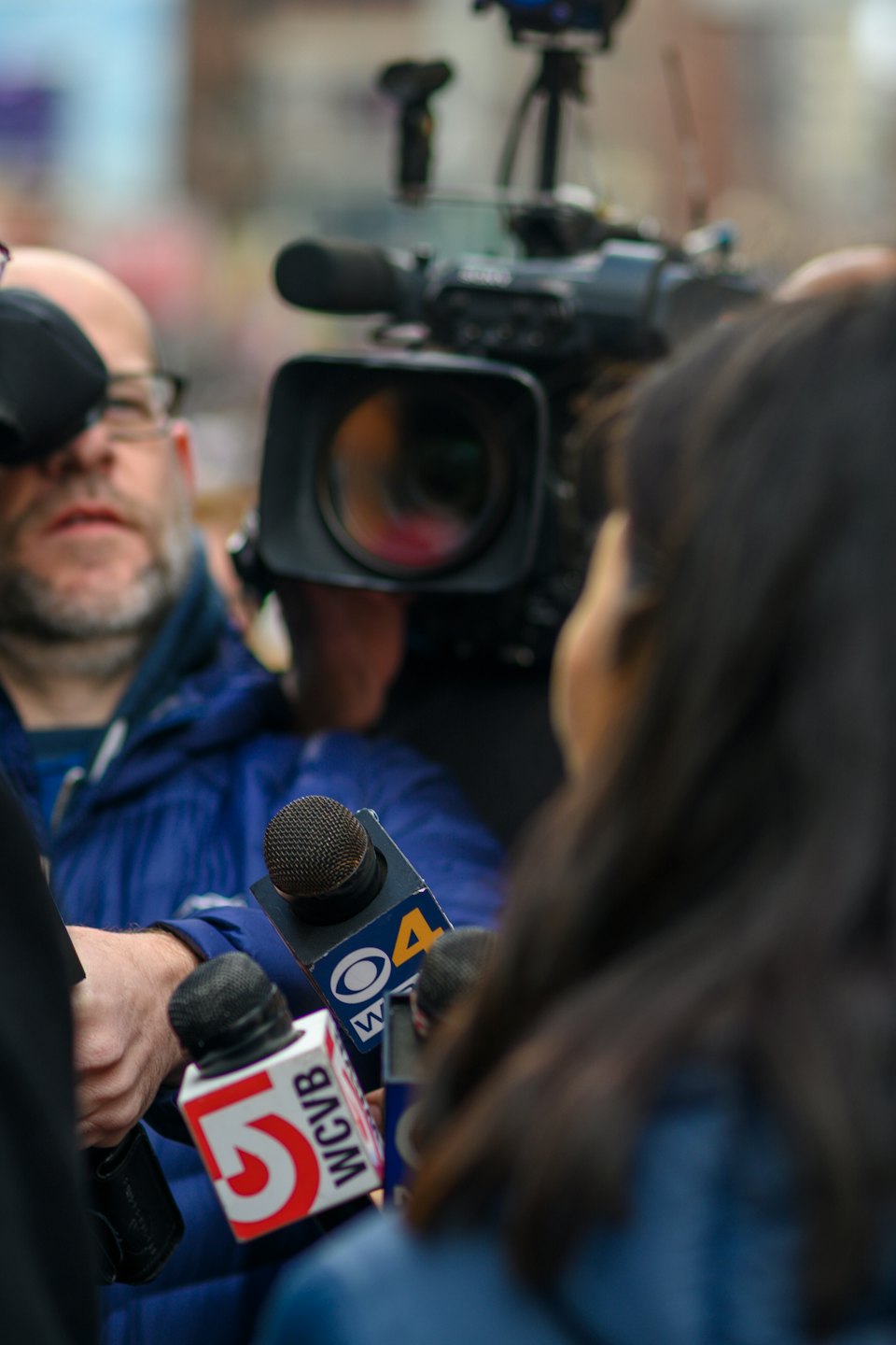 Giornalisti con microfoni intervistano una persona fuori campo.